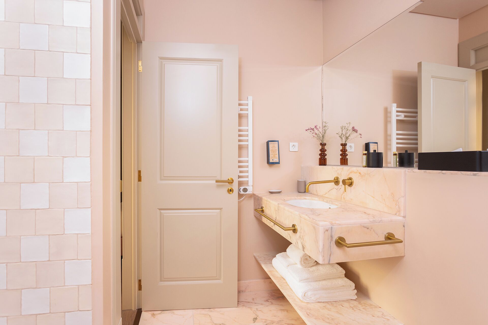 Une salle de bain avec une porte blanche, un lavabo en marbre et un porte-serviettes.