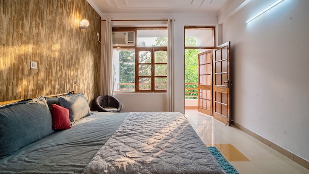 Ein Schlafzimmer mit einem Bett, einer Holzwand, einem Fenster und einer Tür, die auf einen Balkon führt.