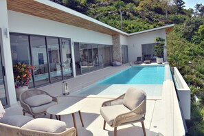 A modern outdoor pool area with lounge chairs and a dining table.