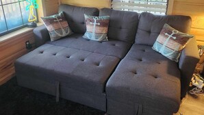 A grey sectional sofa with matching cushions, positioned in front of a window with blinds. - Charming 1-bedroom house with WiFi, AC on the Bayou in beautiful Bay St. Louis (Bay St. Louis)
