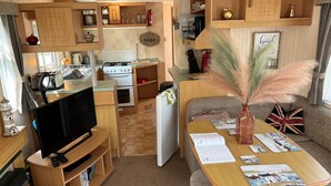 Un espai habitable reduït amb cuineta, televisió, zona de menjador i sofà.