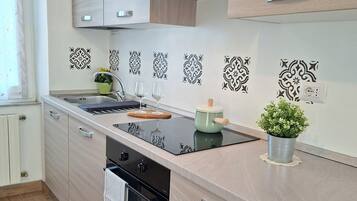 A modern kitchen with a built-in oven, a stovetop, a sink, and wooden cabinets.