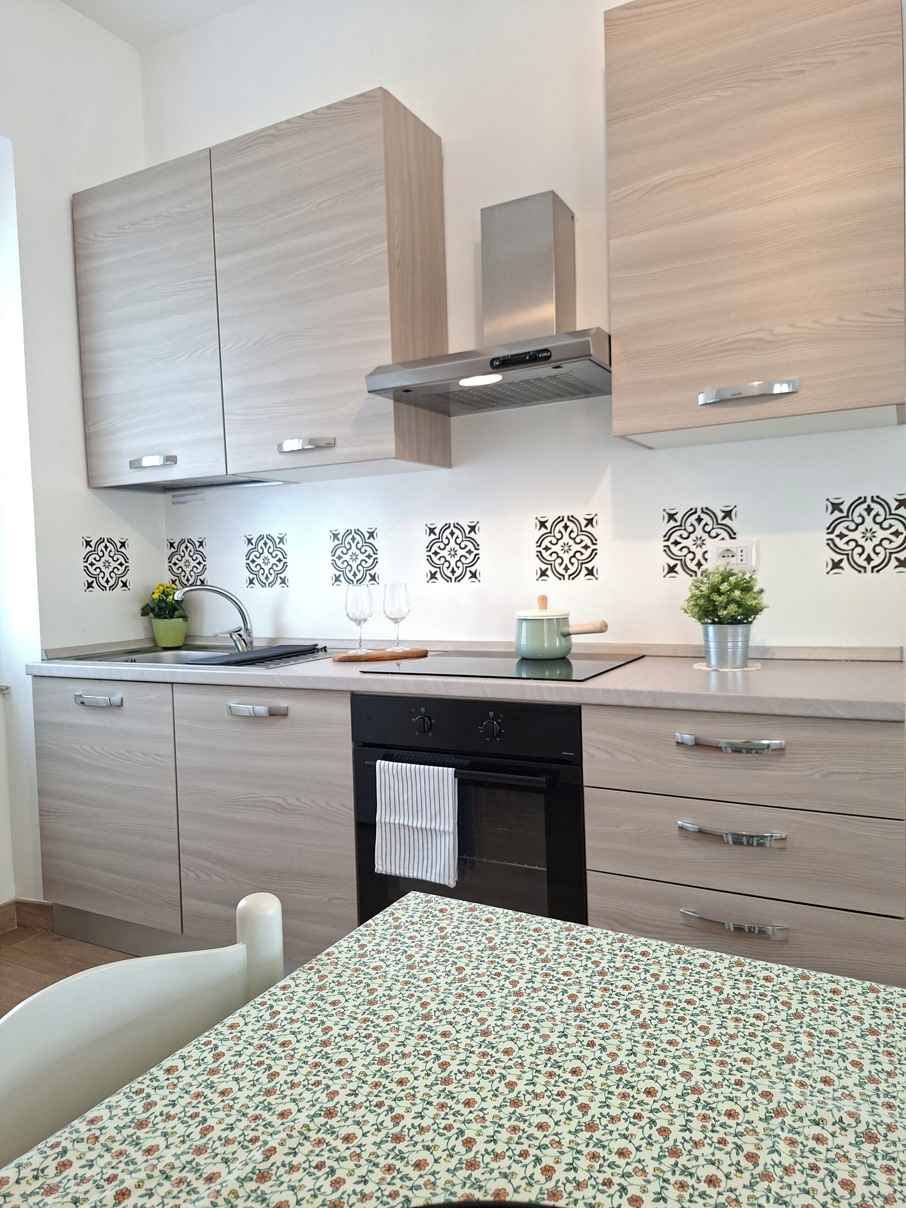 Et moderne køkken med træskabe, indbygget ovn og et mønstret backsplash.
