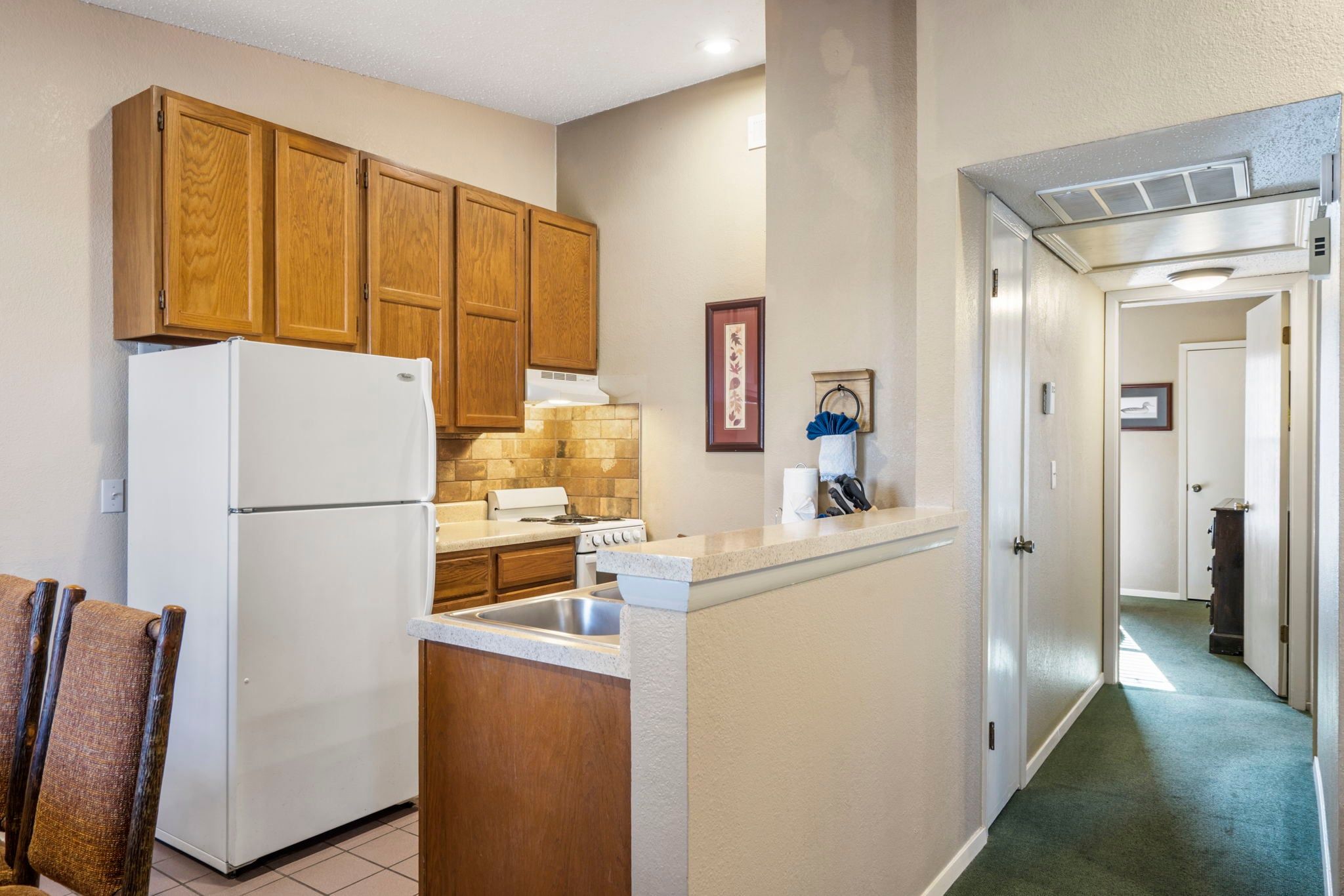 A kitchen with wooden cabinets, a white refrigerator, a stove, and a countertop.