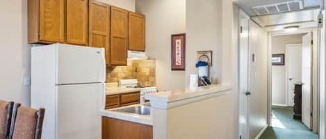 A kitchen with wooden cabinets, a white refrigerator, a stove, and a countertop.