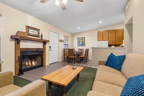 A living room with a fireplace, a dining area, and a kitchen with wooden cabinets.