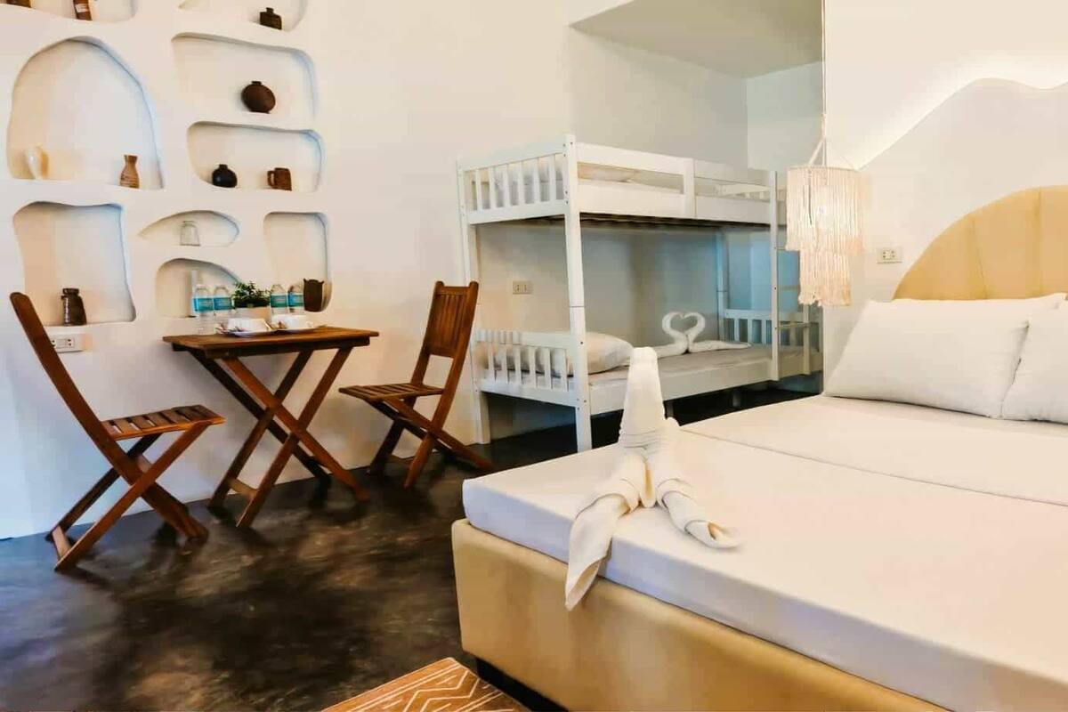 A bedroom with a bunk bed, a small desk with a chair, and a bedside table.