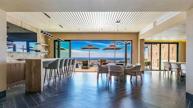 A modern indoor space with a bar area, seating, and large windows offering a view.