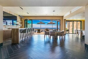 Un espace intérieur moderne doté d’un bar, de coins salon et de grandes fenêtres offrant une vue panoramique.