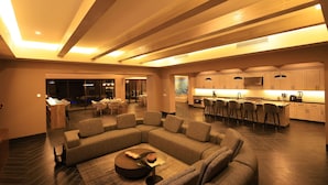 A modern living room with a sectional sofa, a coffee table, and a kitchen area in the background.
