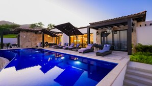 A swimming pool with lounge chairs and a covered patio area.