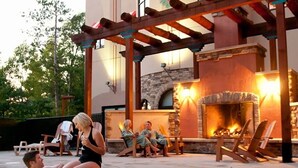 Zona junto a la piscina con chimenea de piedra y sillones de descanso.