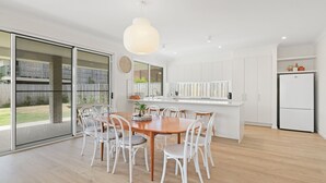 Une cuisine moderne avec un coin repas, des meubles blancs et une grande fenêtre.