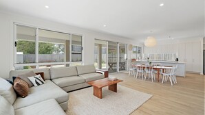 Un salon moderne avec un canapé, une table basse et un coin repas avec des chaises.