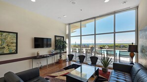 A spacious living area with a large window, a flat-screen TV, and a seating arrangement.
