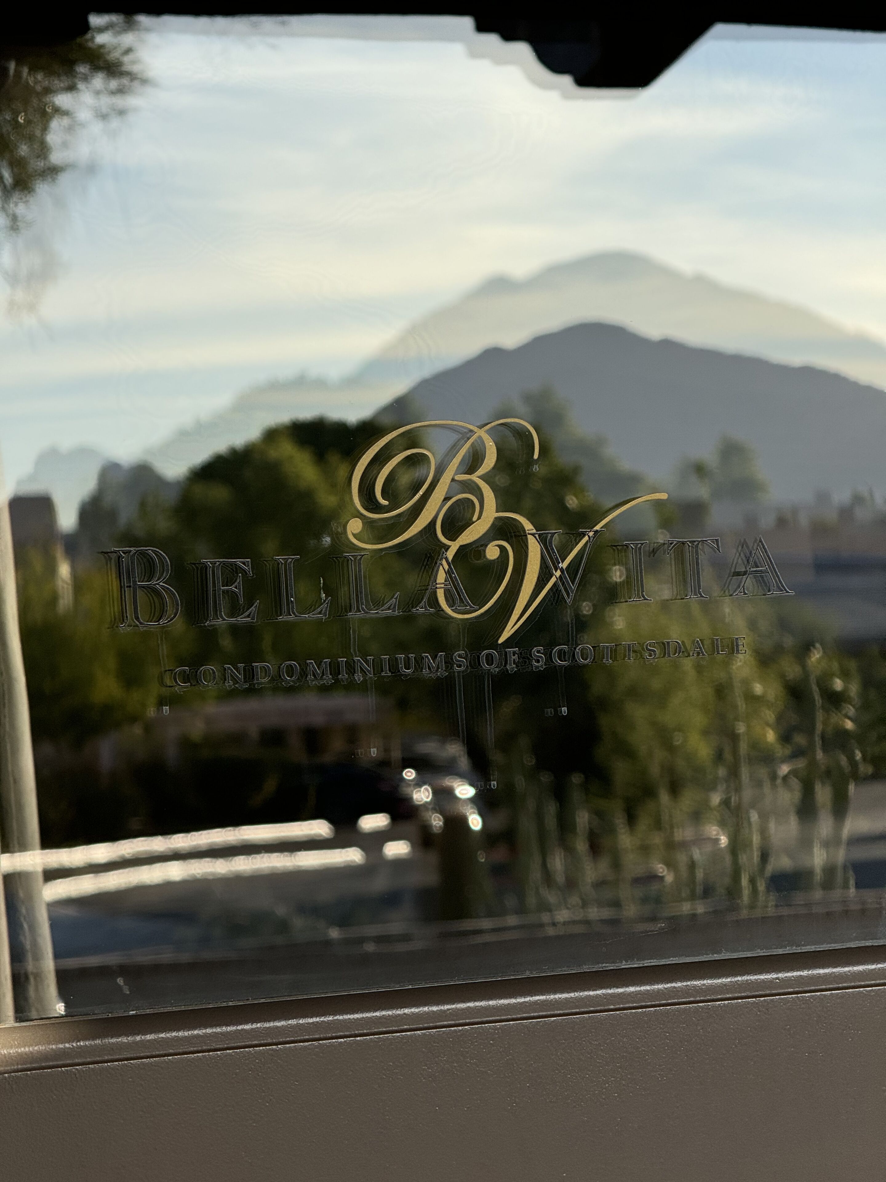 A view through a window with the text "BELLVITA" and "CONDOMINIUMS OF SCOTTSDALE" visible.