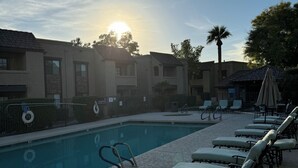 A poolside area with lounge chairs and a pool, surrounded by buildings with a uniform architectural style. - Fully furnished next to Greenbelt and close to Olde Towne & Fashion Square. (Scottsdale)