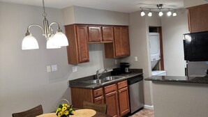 A modern kitchen with granite countertops, wooden cabinets, and a built-in dishwasher. - Fully furnished next to Greenbelt and close to Olde Towne & Fashion Square. (Scottsdale)