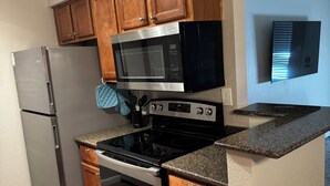 A kitchen with wooden cabinets, a stainless steel refrigerator, a microwave, a stove, and a built-in oven. - Fully furnished next to Greenbelt and close to Olde Towne & Fashion Square. (Scottsdale)