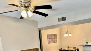 A living room with a sectional sofa, a coffee table, a ceiling fan, and a dining area in the background. - Fully furnished next to Greenbelt and close to Olde Towne & Fashion Square. (Scottsdale)