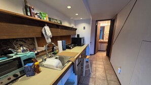 A modern kitchen with a built-in oven, a sink, and a microwave. There is a wooden shelf above the sink with various items, including a bottle of olive oil and a box of pasta. - Pet friendly 1 bedroom, in the heart of Snowmass Vlg (Snowmass Village)