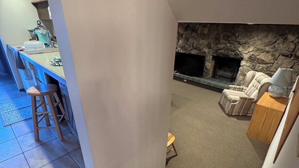 A staircase leading to a living area with a stone fireplace, a dining area with a kitchen in the background, and a small stool near the stairs. - Pet friendly 1 bedroom, in the heart of Snowmass Vlg (Snowmass Village)