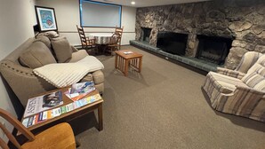 A living room with a stone fireplace, a sofa, a striped armchair, and a coffee table with magazines. - Pet friendly 1 bedroom, in the heart of Snowmass Vlg (Snowmass Village)