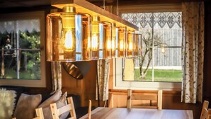 A dining area with a wooden table, chairs, and a fur rug. A chandelier hangs above the table. - Quaint vacation home in the mountains - pure relaxation and nature! (Lingenau)