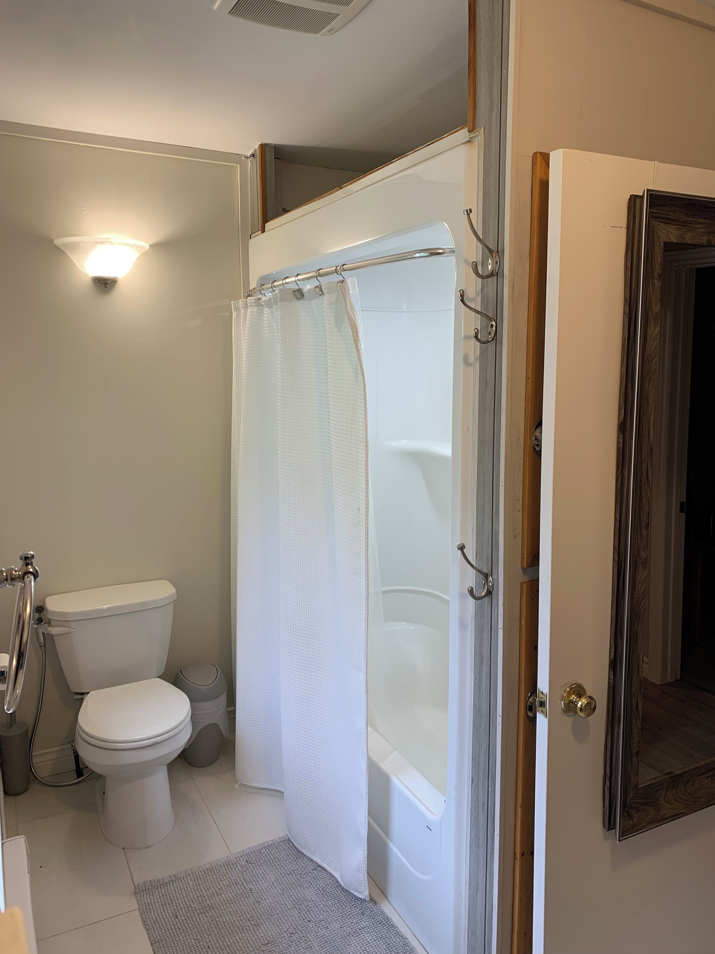 A bathroom with a toilet, a shower with a white curtain, and a bathtub.