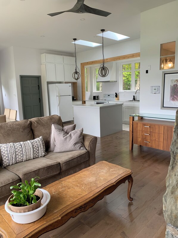 A modern living room with a sofa, coffee table, and a potted plant. - Private home on 8 acres of wooded and flower-filled grounds at Wentworth Lake (Moodys Corner)