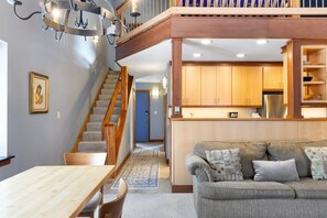 Un intérieur moderne avec un escalier menant à une mezzanine, un coin repas et une cuisine dotée de meubles en bois.