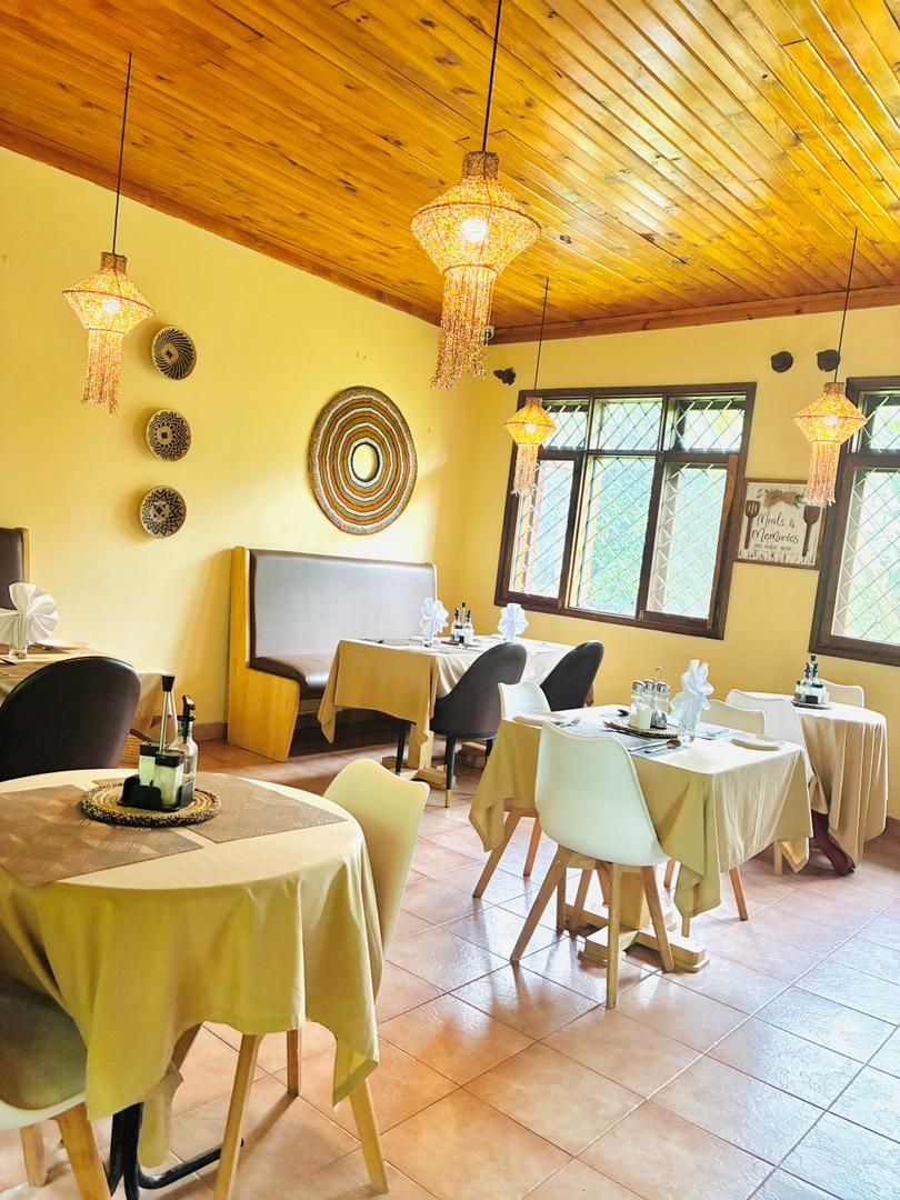 A dining area with round tables, chairs, and hanging light fixtures.
