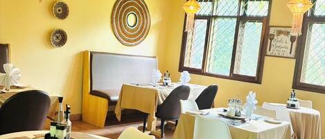 A dining area with round tables, chairs, and hanging light fixtures.