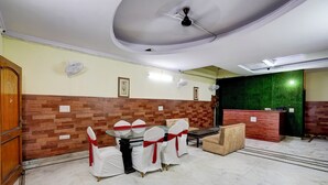Una hall d'albergo con una reception, una sala da pranzo con tavolo e sedie, e un soffitto decorativo.