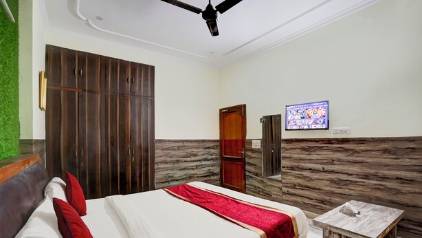 Una camera d'albergo con un letto, un armadio in legno, una televisione e un tavolino.