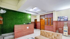 Un'area reception con parete verde, scrivania in legno, una poltrona, un erogatore di acqua e una ventola a soffitto.
