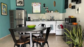 A compact kitchen with a dining table, chairs, a refrigerator, a microwave, and a stove.