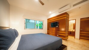 A bedroom with a bed, a TV mounted on the wall, a window, and a bathroom visible through an open door. - 2 Br Condo Near to the Beach - CDM 113 (Playa del Carmen)