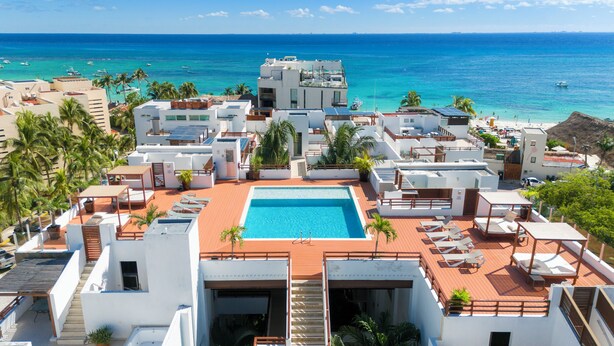 A rooftop pool with a view of the ocean, surrounded by modern buildings and palm trees. - 2 Br Condo Near to the Beach - CDM 113 (Playa del Carmen)