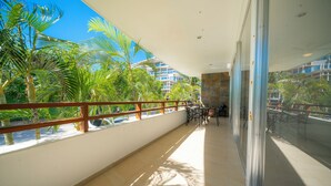 A balcony with a view of palm trees and a building in the background. - 2 Br Condo Near to the Beach - CDM 113 (Playa del Carmen)