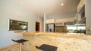 A modern kitchen with granite countertops, stainless steel appliances, and two bar stools. - 2 Br Condo Near to the Beach - CDM 113 (Playa del Carmen)