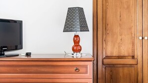 Un aparador de madera con cajones, un televisor y una lámpara.