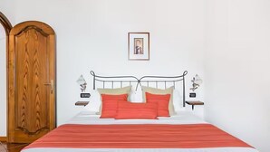 Un dormitorio con cama, puerta de madera y un cuadro enmarcado en la pared.