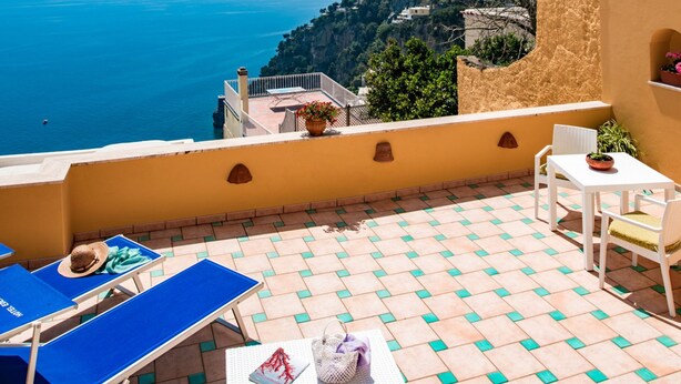 Una terraza con vistas al mar, una mesa con una planta y un sillón azul.