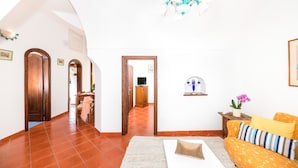 Amplia sala de estar con un sofá, una mesa de centro y un televisor al fondo.