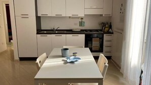 A modern kitchen with white cabinets, a dining table with chairs, and a stove.