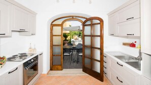Une cuisine avec des meubles blancs, une cuisinière et une grande fenêtre.