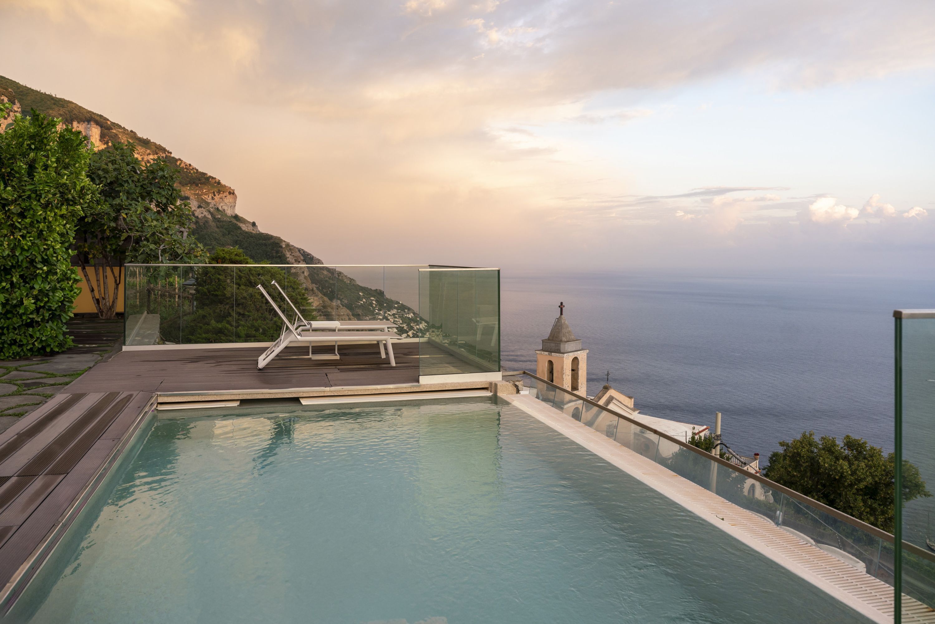 Een dakzwembad met oneindige horizon, een glazen balustrade, een ligstoel en uitzicht op de oceaan.