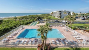 Un hôtel doté d’une grande piscine, de chaises longues et offrant une vue sur l’océan.