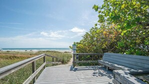 Une promenade en bois mène à un banc d’où l’on a vue sur la plage.